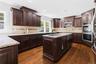 Kitchen featuring dark wood cabinetry, light-colored countertops, hardwood flooring, and stainless steel double ovens
