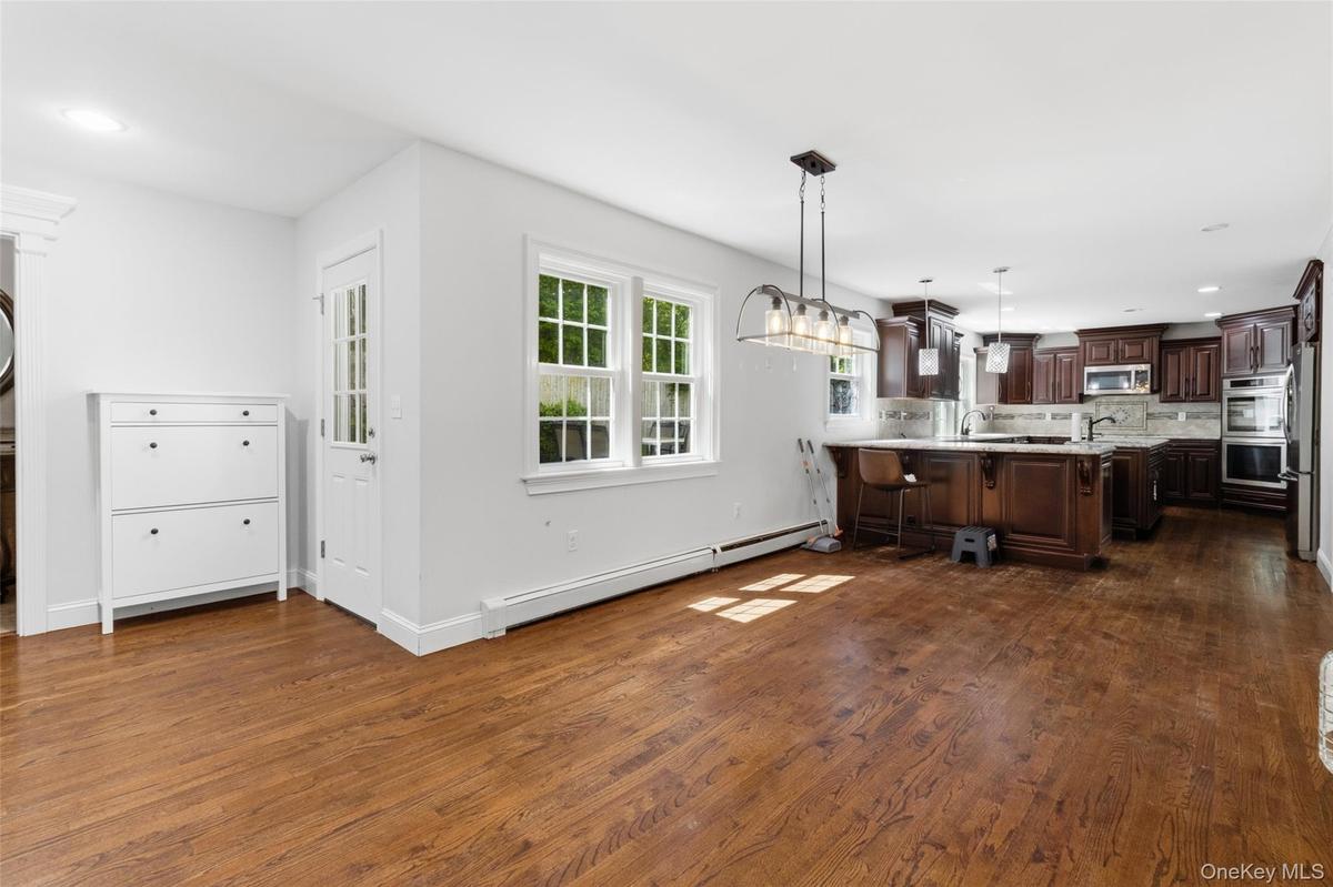 Open-concept kitchen and dining area featuring wood-finish flooring, white trim, and a window with grid detailing