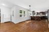 Open-concept kitchen and dining area featuring wood-finish flooring, white trim, and a window with grid detailing