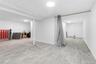 Spacious lower level featuring light gray wood-finish flooring, recessed circular lighting, and painted support columns