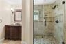Glass-enclosed shower with mosaic tile floor and beige wall tiling featuring decorative accents