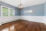 Hardwood flooring, two-tone wall treatment with wainscoting, and a decorative orb chandelier