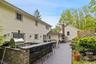 Expansive outdoor living area featuring a multi-level composite deck, built-in stone veneer outdoor kitchen with a stainless steel pizza oven, and a s