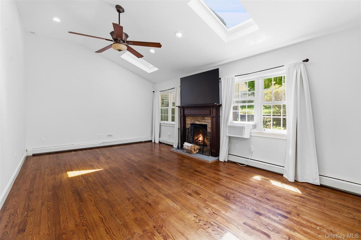 Spacious room featuring vaulted ceilings, fire place, recessed lighting, and rich wood-finish flooring
