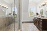 Glass-enclosed shower with a chrome handle, featuring tile walls and flooring