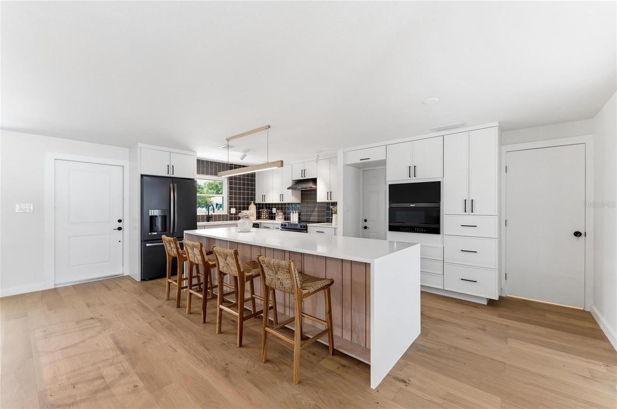 Step into the home through the front door and one sees a brand new open kitchen with a ceramic and stone backsplash, quartz countertops and island top