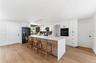 Step into the home through the front door and one sees a brand new open kitchen with a ceramic and stone backsplash, quartz countertops and island top