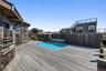 Facing the expansive deck area with the pool and seating area in view