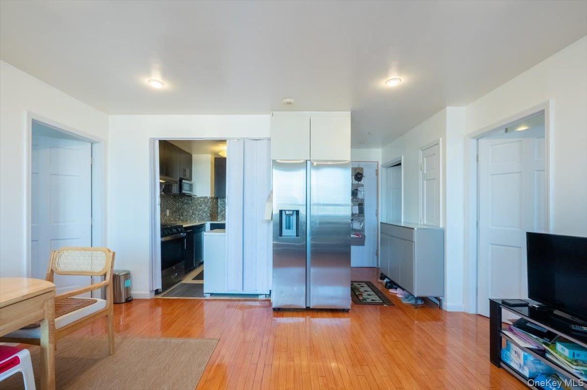 Kitchen with stainless steel fridge with ice dispenser, light wood-style floors, backsplash, range with gas stovetop, and white cabinets