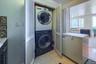 Laundry area with stacked washer / drying machine and light tile patterned flooring