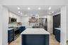 Renovated kitchen with navy shaker cabinetry, white marble counters and backsplash, farmhouse apron sink, brass hardware, and a marble-topped center i