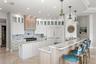 An elegant chef's kitchen appointed with quartz surfaces and statement designer lighting.