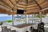 Outdoor kitchen with bar, tiki hut and TV.