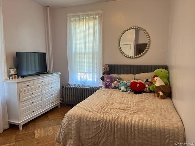 Bedroom featuring wood-finish parquet flooring and a window with blinds