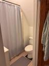 Compact bathroom featuring a white toilet, light-toned square floor tiles, and a white vanity with a countertop