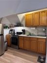 Compact kitchen featuring wood-finish cabinetry and a stainless steel appliance suite