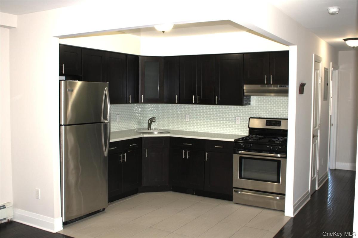 Kitchen featuring dark wood-finish cabinetry, light-toned countertops, a full stainless steel appliance package, and a subway tile backsplash