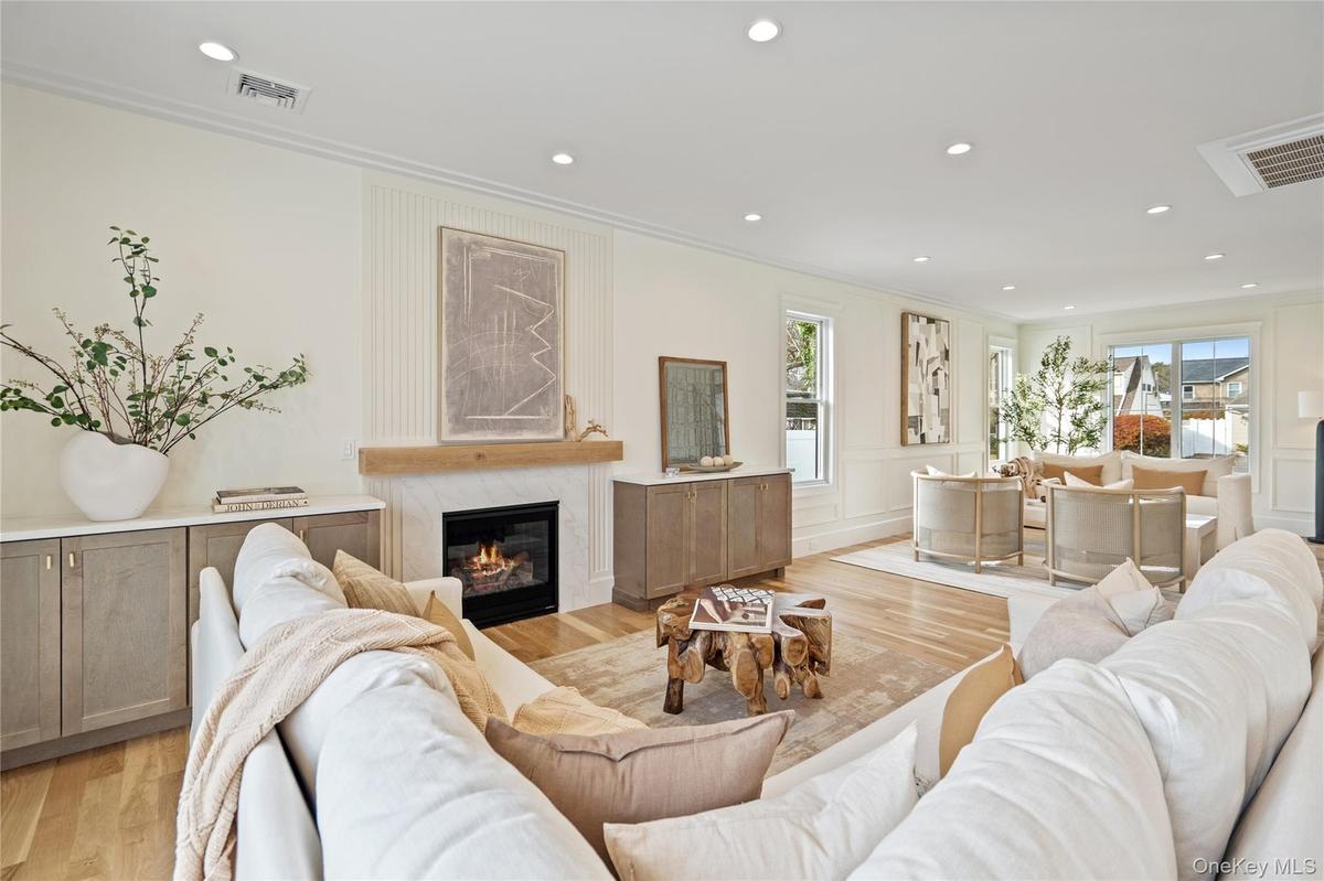 Living room with light wood finished floors, a premium fireplace, recessed lighting, plenty of natural light, and crown molding