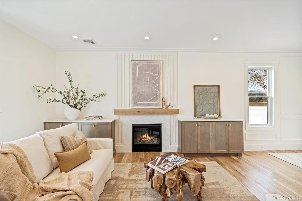 Living room featuring a high end fireplace, recessed lighting, light wood-style floors, crown molding, and a decorative wall