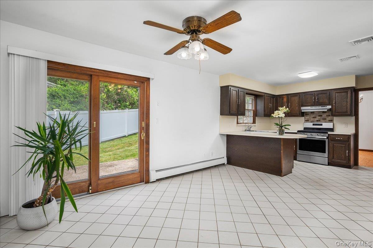 Kitchen area featuring a breakfast bar with light-toned countertops, dark wood-finish cabinetry, and stainless steel appliances