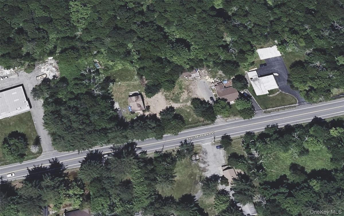 Aerial perspective showcasing the property with significant tree coverage and direct road frontage
