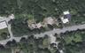 Aerial perspective showcasing the property with significant tree coverage and direct road frontage
