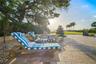 Expansive poolside setting with multiple lounging areas across beautifully landscaped grounds.