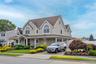 View of front facade with a porch, decorative driveway, a shingled roof, and a front yard