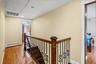 Stairway featuring attic access, wood-type flooring, and a baseboard heating unit