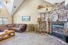 Living area with high vaulted ceiling, plenty of natural light, a fireplace, and a chandelier