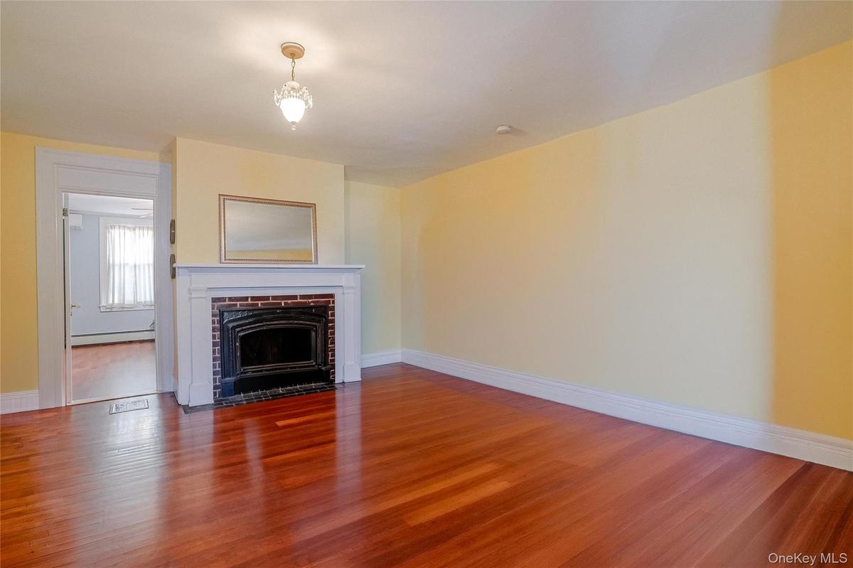 The beautiful living room features gleaming hardwood floors and a stunning fireplace, creating a warm and inviting space perfect for relaxing or enter