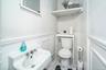 Half bath with toilet, marble look tiles, and wainscoting