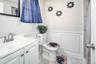 Bathroom with marble finish flooring, wainscoting, vanity, and toilet