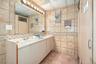 Bathroom featuring tile walls, double vanity, a shower, a paneled ceiling, and backsplash