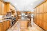 Kitchen featuring high quality appliances, backsplash, light stone countertops, a breakfast bar, and glass insert cabinets