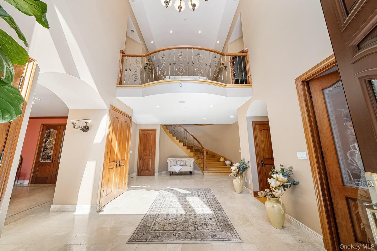 Entrance foyer with arched walkways, high vaulted ceiling, stairs, and recessed lighting