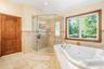 Full bath featuring a jetted tub, a shower stall, tile patterned floors, and lofted ceiling