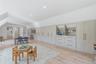 Spacious room featuring extensive built-in cabinetry with integrated shelving and drawers, light wood-finish flooring, recessed lighting, and white wa