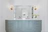 Dual vanity with a white countertop and light blue cabinetry featuring gold-tone hardware