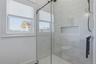 Modern shower enclosure featuring a sliding glass door, subway tile surround, built-in niche, and matte black hardware