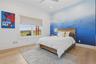 Bedroom featuring a broad window with expansive outdoor scenery, a distinctive blue gradient accent wall, wood-finish flooring, and a ceiling fan