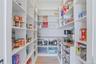 Walk-in pantry featuring extensive white shelving, wood-finish flooring, a wood-finish countertop, under-counter storage, and built-in wire baskets