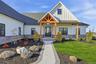 Modern farmhouse exterior featuring white siding, a dark roof, and stone facade accents