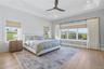 Spacious bedroom featuring light wood-finish flooring, a tray ceiling, recessed lighting, and a modern ceiling fan