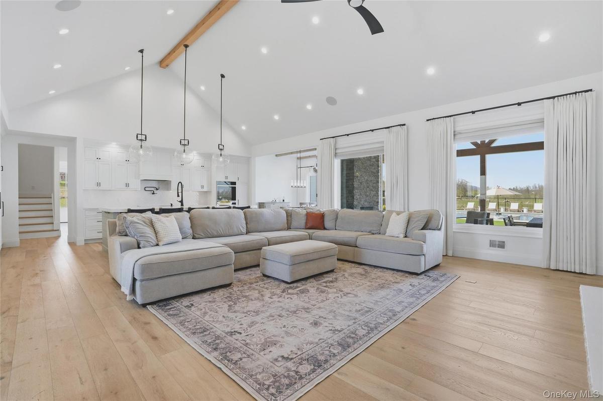 Vaulted ceiling with an exposed wood beam, recessed lighting, and light wood-finish flooring
