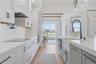 Modern kitchen featuring white cabinetry with matte black hardware, white herringbone tile backsplash, and light wood-finish flooring