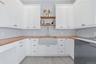 Laundry area featuring extensive white shaker cabinetry, butcher block countertops, a large farmhouse-style sink with a gooseneck faucet, two open woo