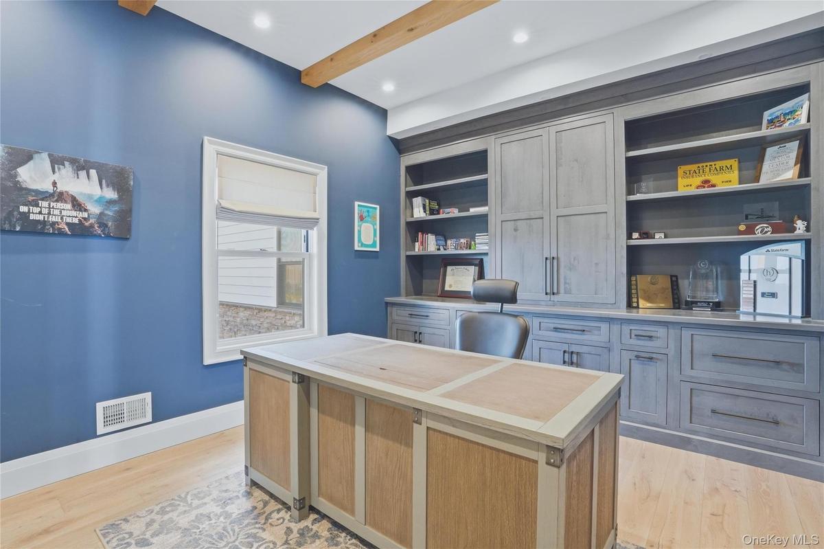 Expansive built-in cabinetry with integrated shelving and drawers, wood-finish flooring, high ceilings with exposed wood beams, and recessed lighting