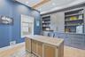Expansive built-in cabinetry with integrated shelving and drawers, wood-finish flooring, high ceilings with exposed wood beams, and recessed lighting