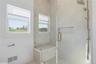 Frameless glass shower enclosure featuring a built-in bench, recessed shelf, and multi-function showerhead